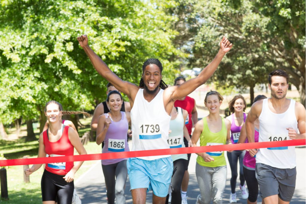 A man celebrating a win from a marathon who experienced eustress vs distress.