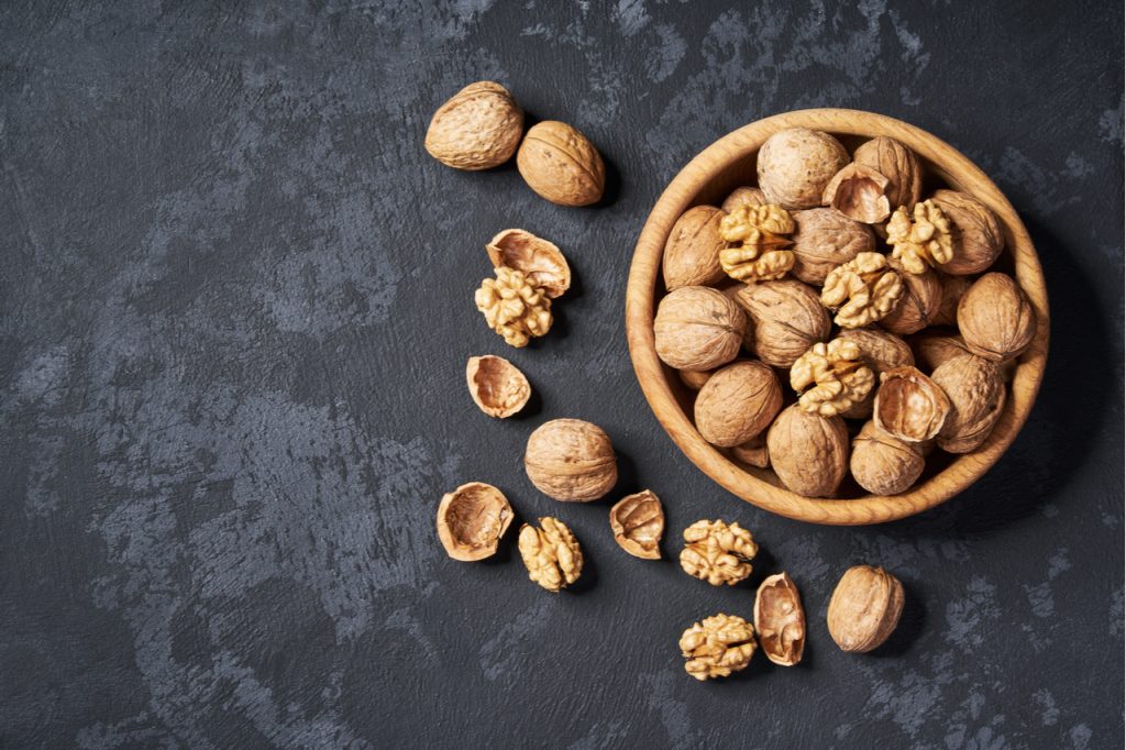 A bowl of walnuts in a black background.