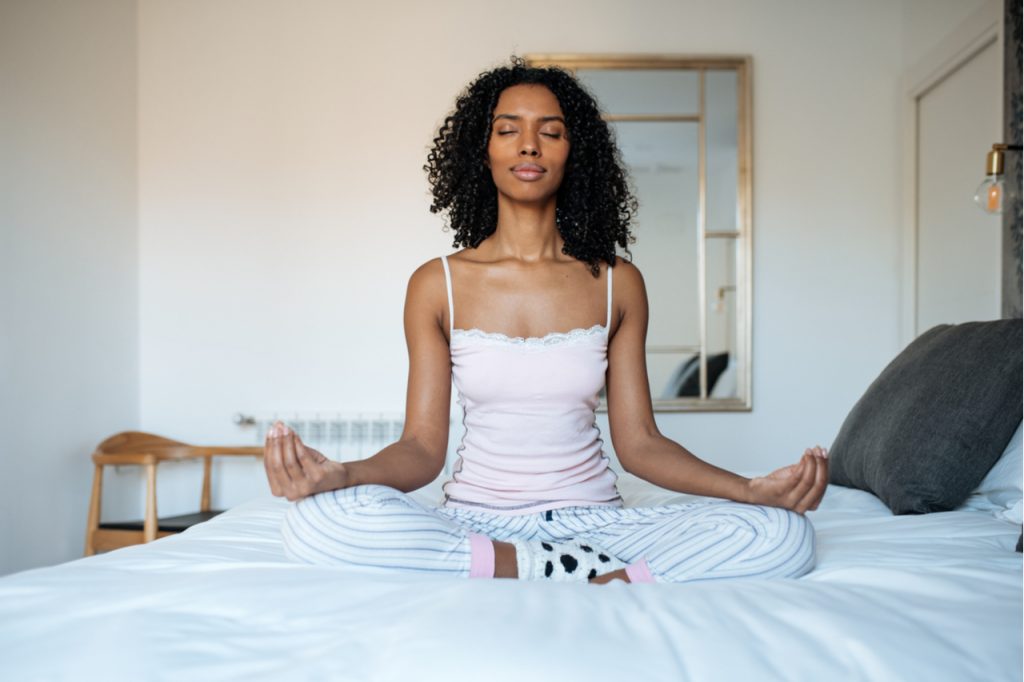 Woman meditating in bed after waking up.