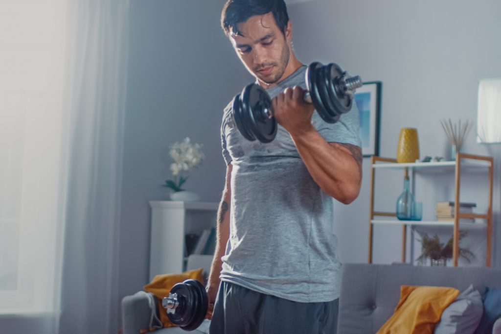 A man lifting dumbbells at home.