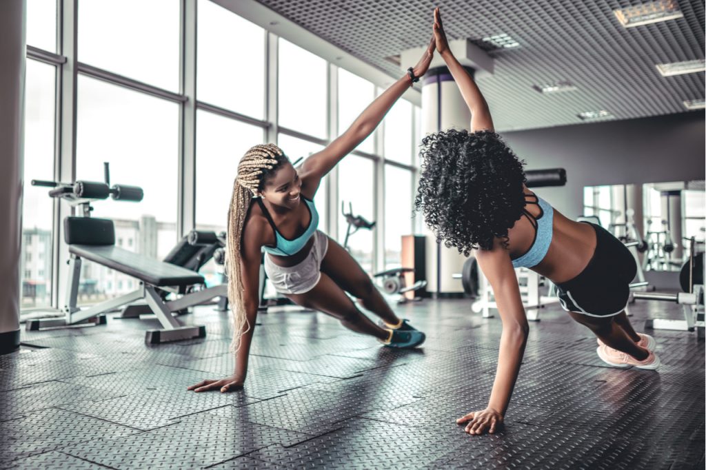 Sporty women giving high fives at the gym while working out.