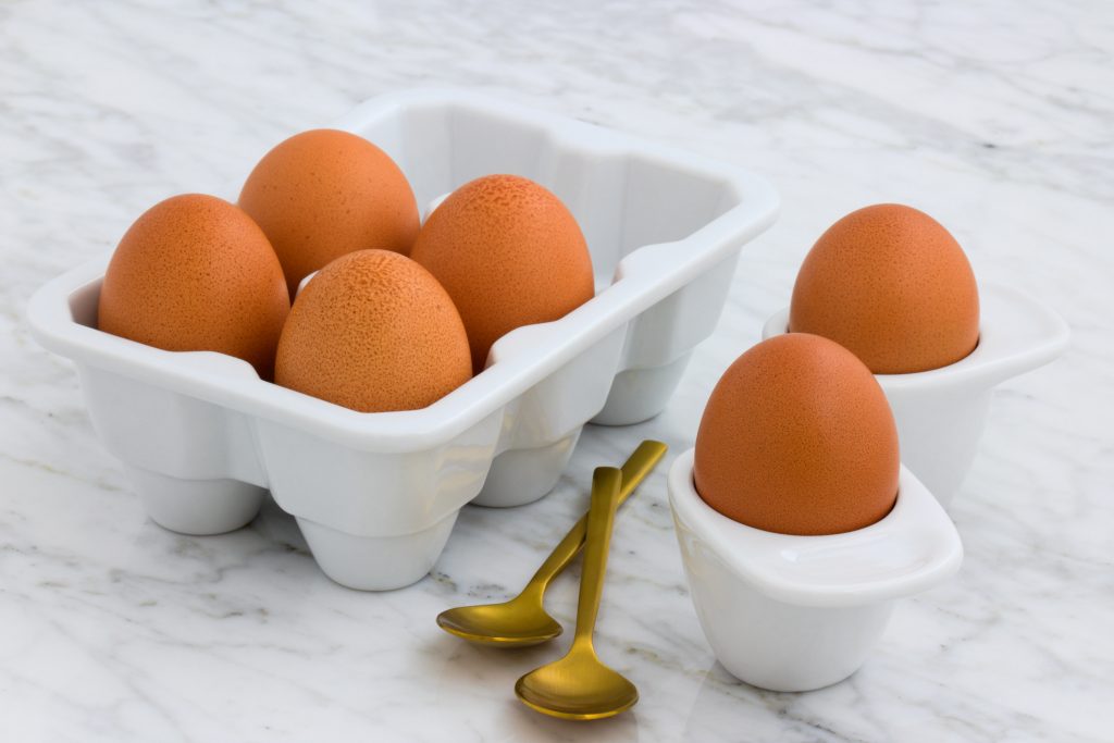A tray of eggs next to 2 spoons foods for healthy skin.