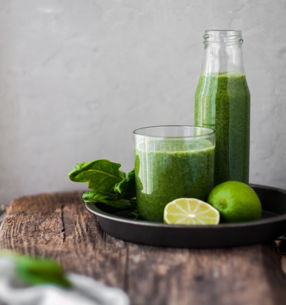 A jar and a glass of a green healthy smoothie made from fruits and vegetables.
