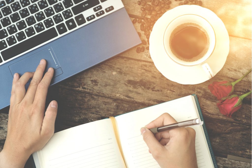 Coffee cup with man using laptop and writing notes on old wood background vintage tone .