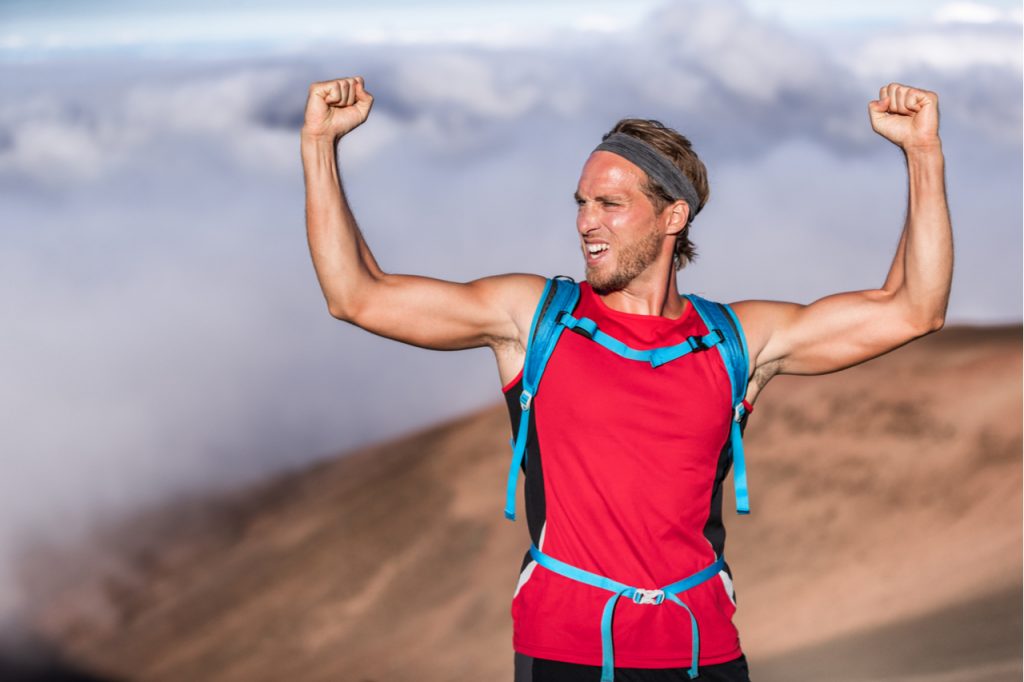 Athlete man screaming with fists up in the air winner arms up