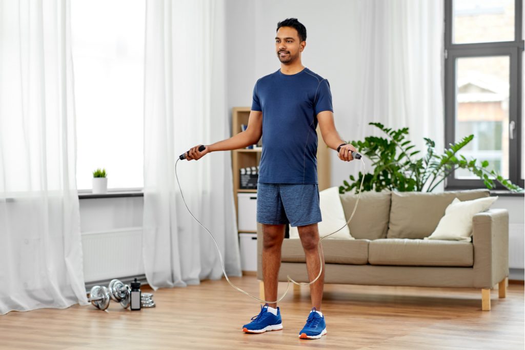 A man doing jumping jacks on his living room.