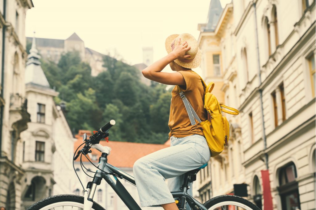 A woman student riding a bike looking for cheapest places travel.