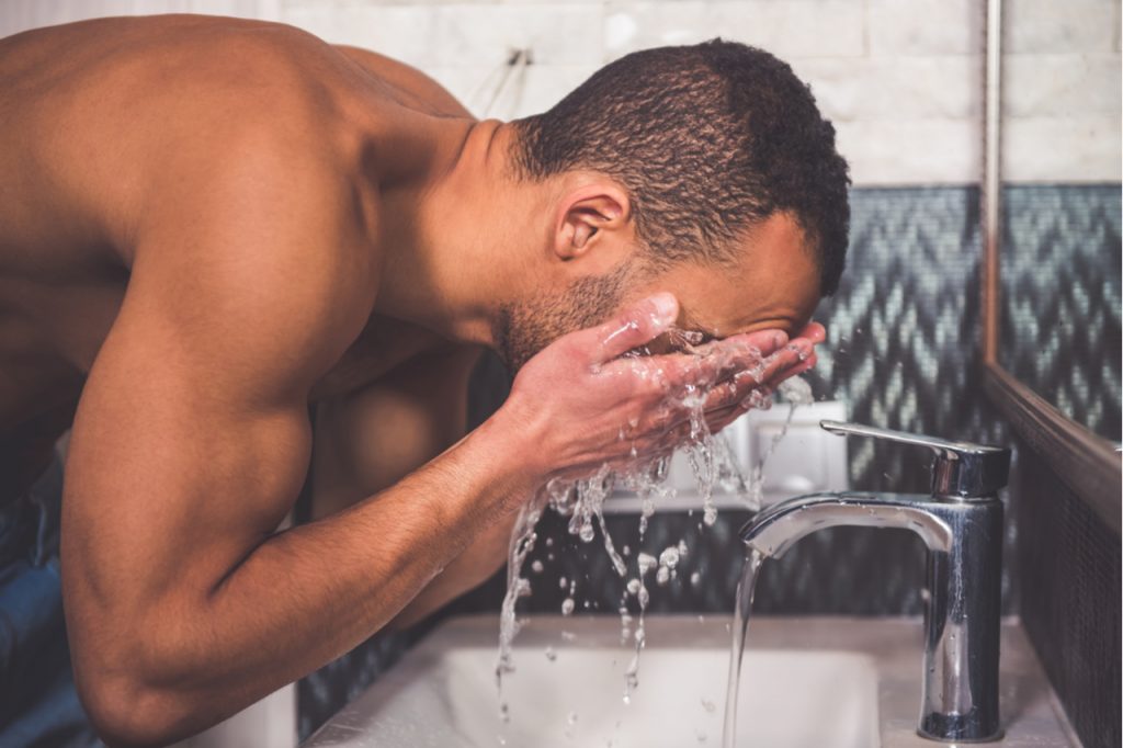 A man washes his face for good hygiene.