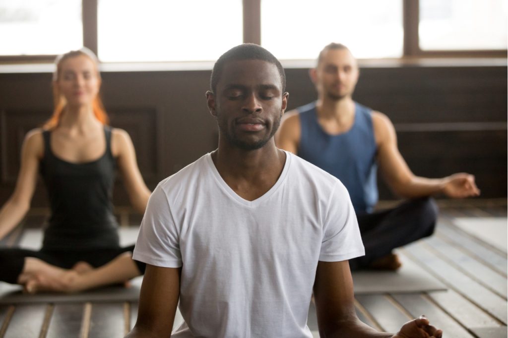 A group of people meditating as part of self-care.