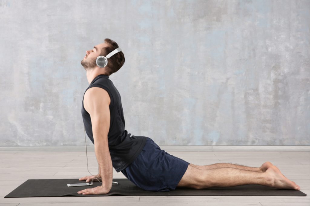 A man enjoying his music while doing yoga.