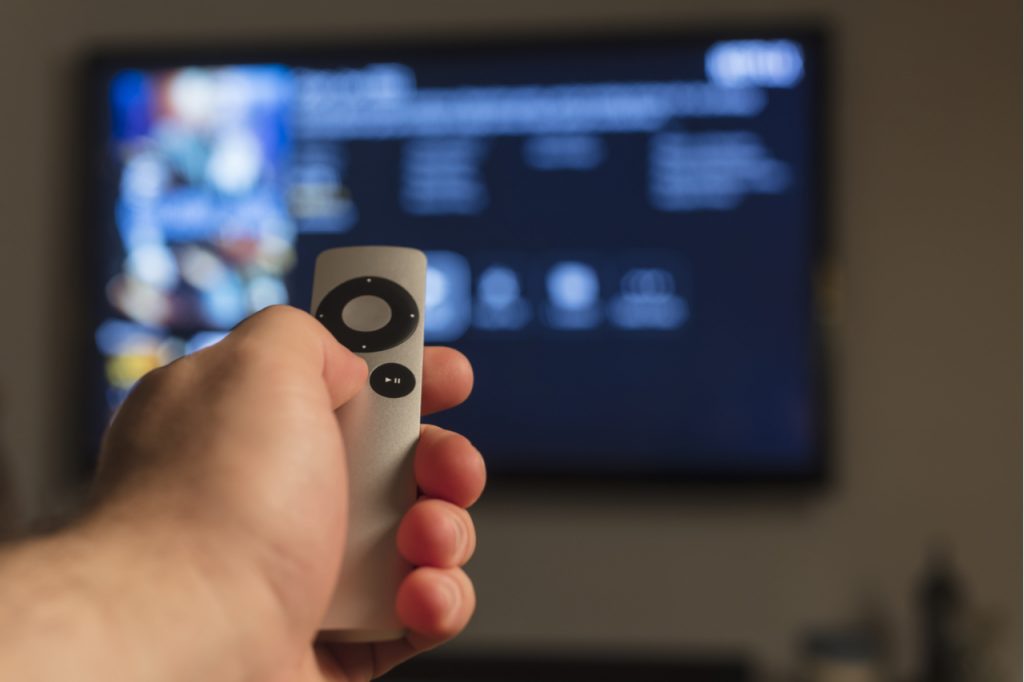 Hand holding a remote control to watch a movie.
