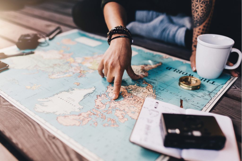 An image of a woman student checking the world map to plan a vacation.