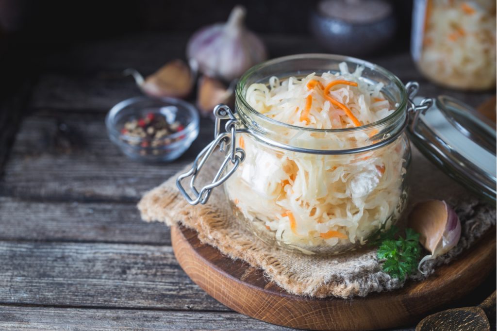 Glass jar with homemade sauerkraut on rustic wooden table