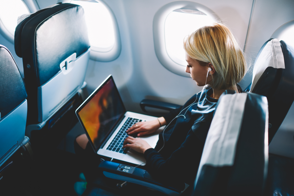 A woman on a plane while working on her laptop.