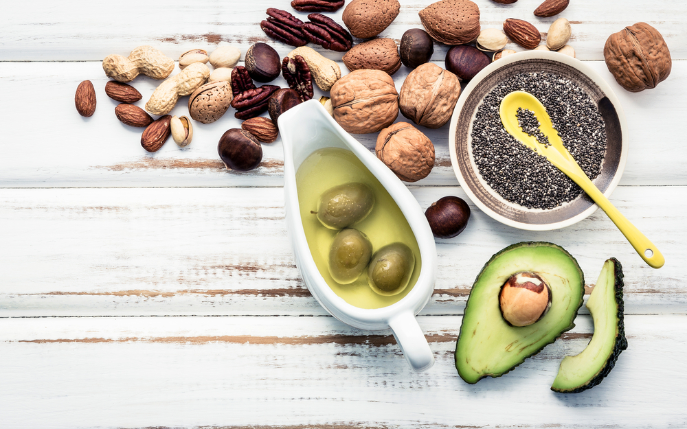 Olives, sliced avocado, a bowl of chia seeds, and variety of nuts.