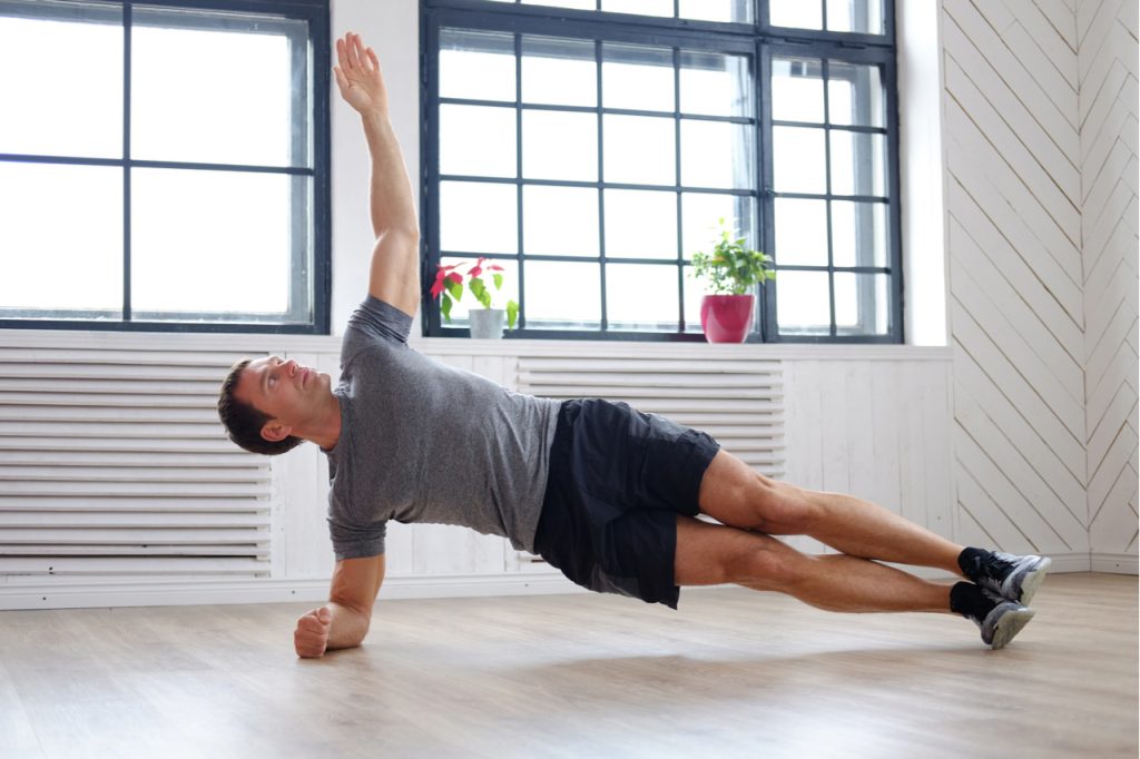 A man doing side plank workout position at home