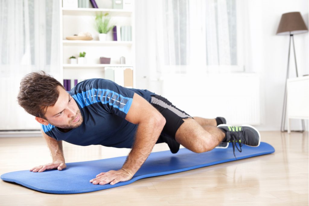 A man doing the spider-man plank in his living room