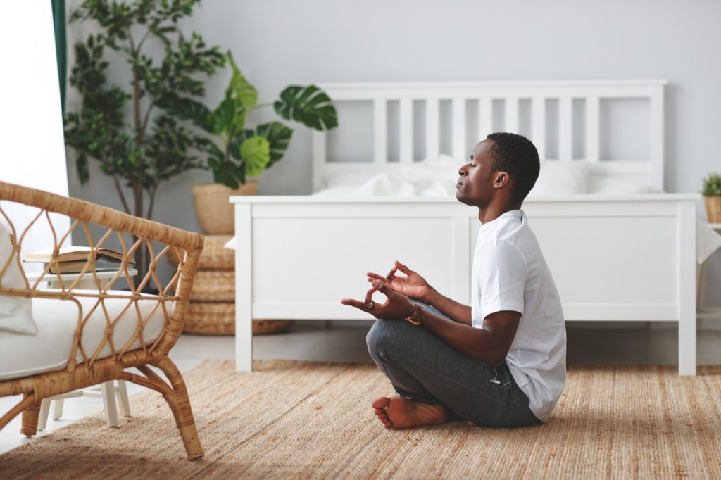 A man meditating after waking up early morning trying to keep away from being technology addict.