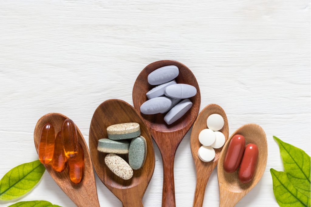 A selection of supplements on 5 different wooden spoons like the alpha brain by onnit.