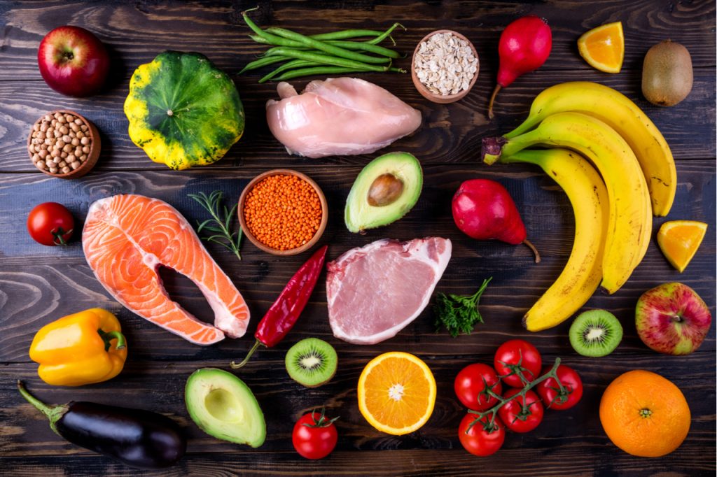 Healthy diet with fish, meat, grains, vegetables, fruits on wooden table.