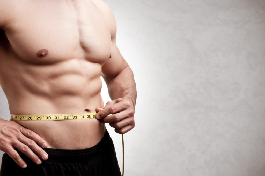 A man measuring his waist for progress.
