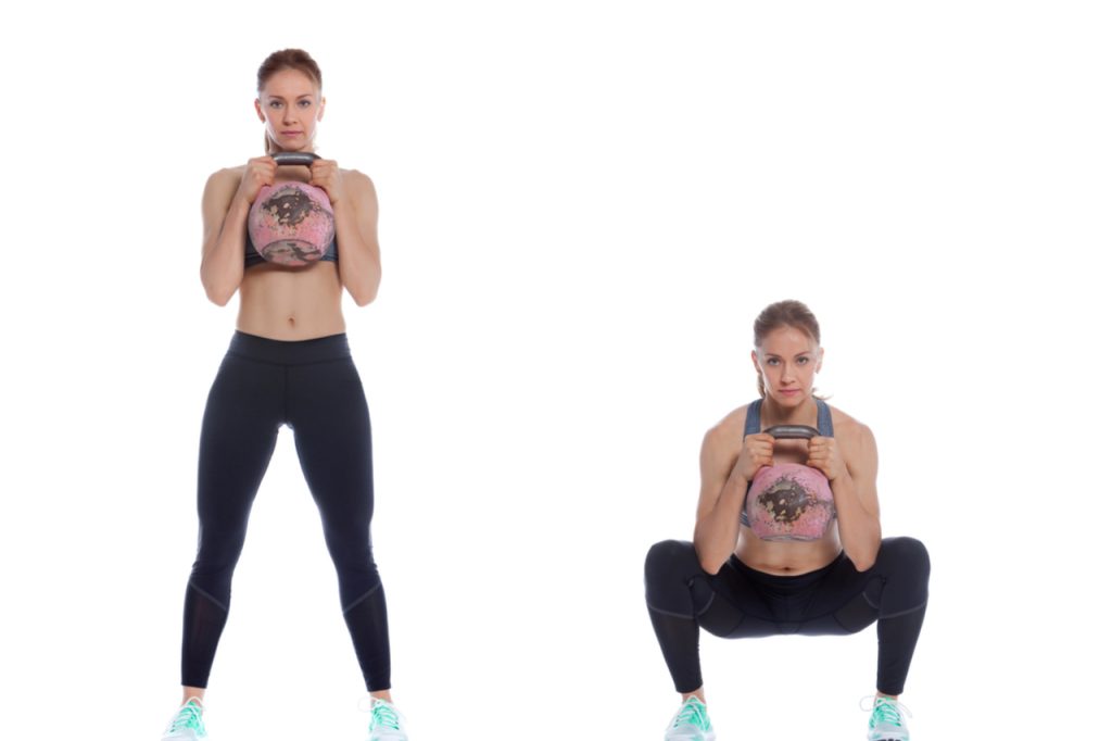 A fit woman showing how to do goblet squats.