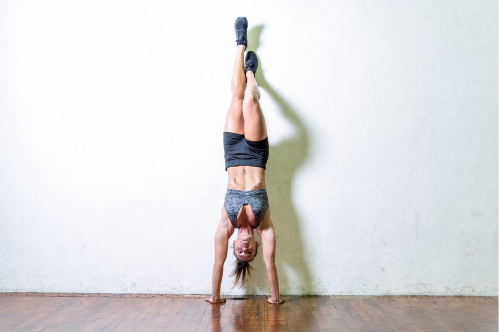 A woman doing a handstand wall walk.