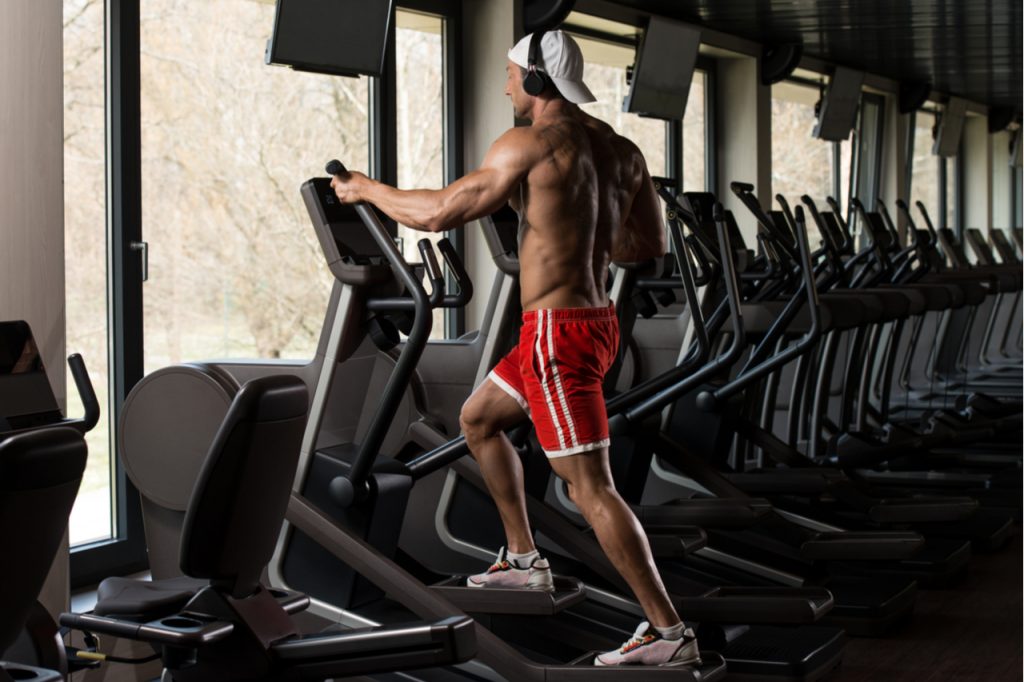 A fit man doing aerobics elliptical walker as cardio.