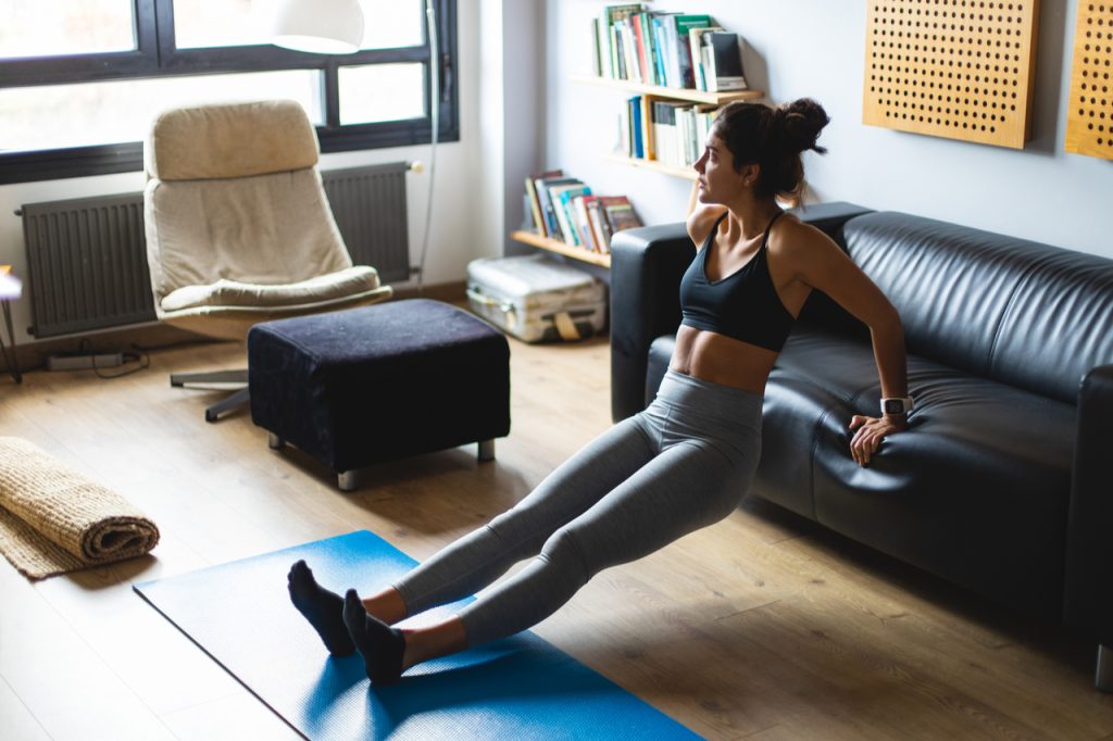 A woman doing a dip exercise at home for her arm workout.