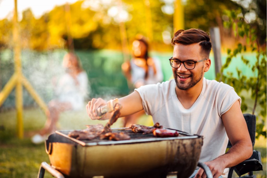 A man cooking some meat on a barbecue grill.