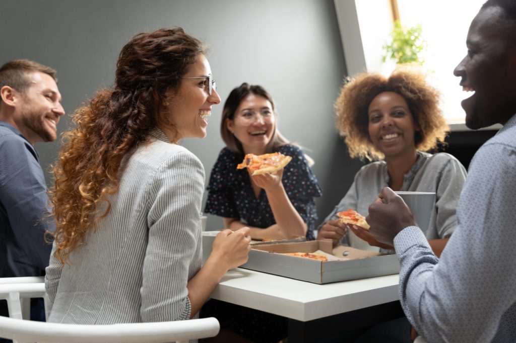 Cheerful multiracial business team people having fun eat pizza together.