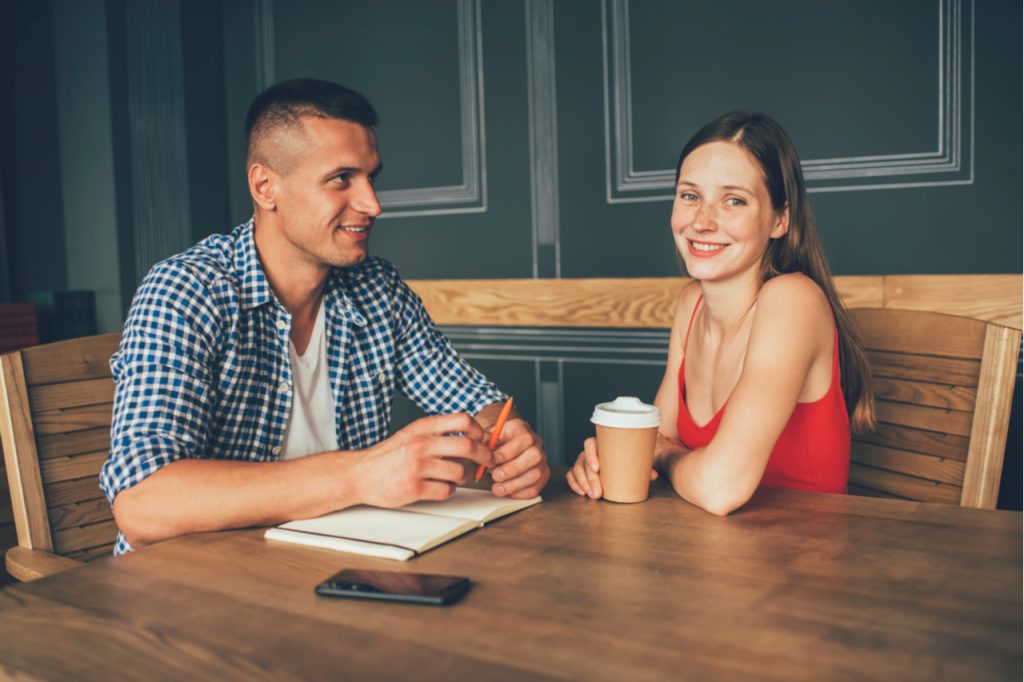 Couple talking and journaling over coffee happily.