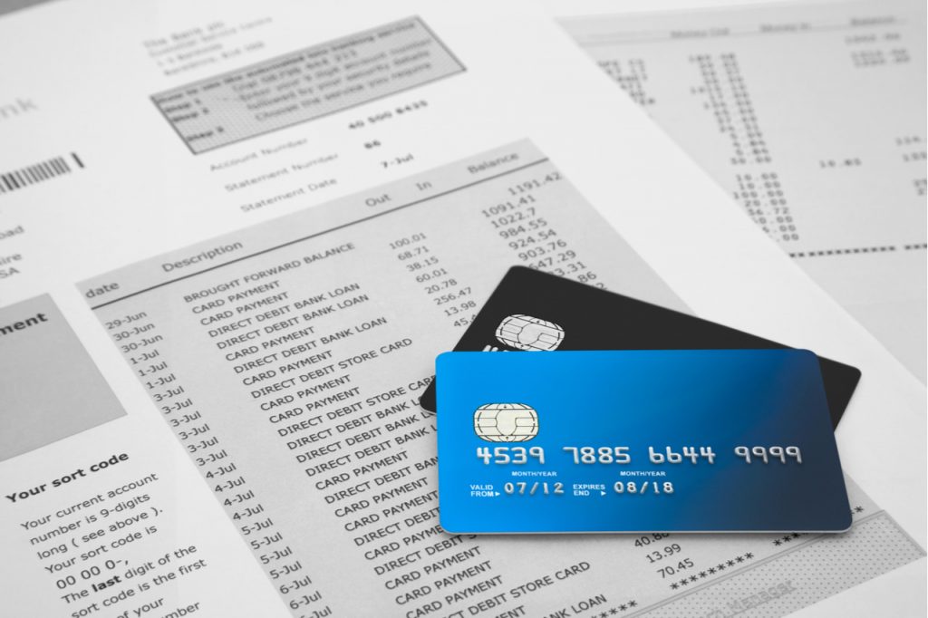 Two credit cards on top of a credit card billing statement.