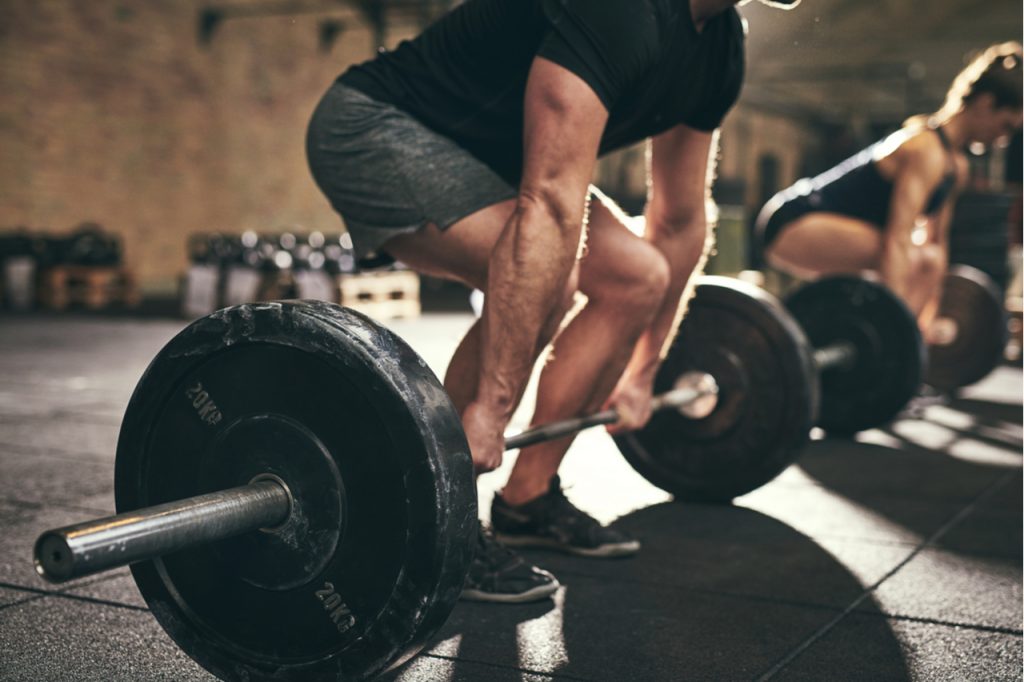 A man and a woman doing deadlift exercises.