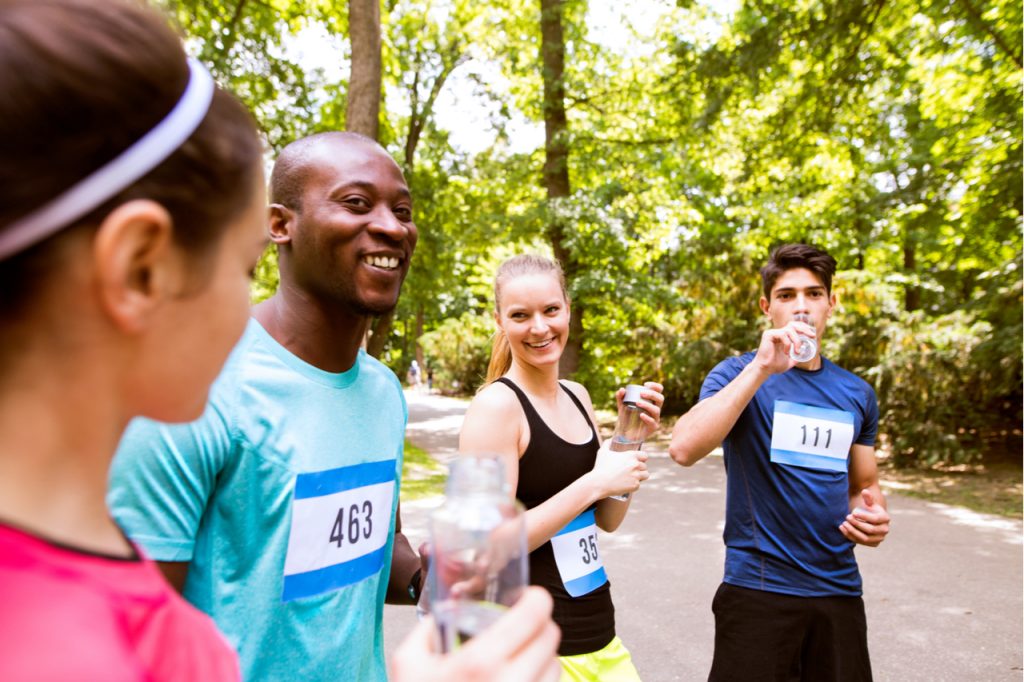 Group of young athletes drinking water after running.