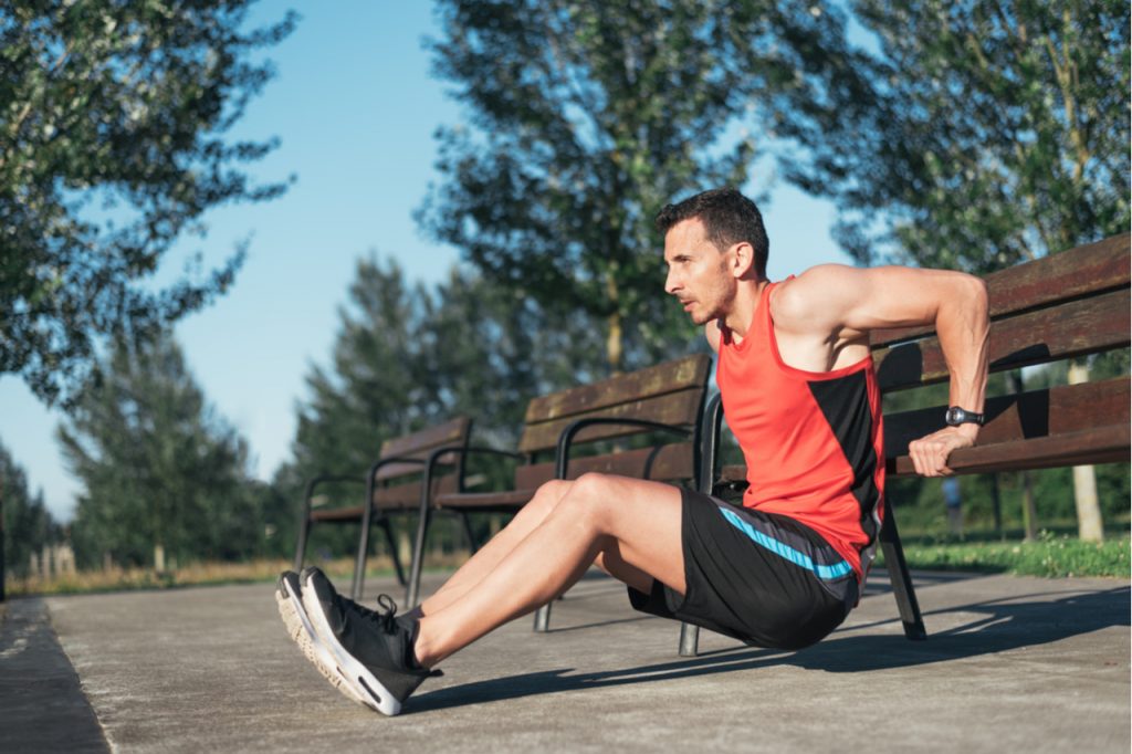Fitness man doing bench triceps dips during workouts for outside cross training workout.