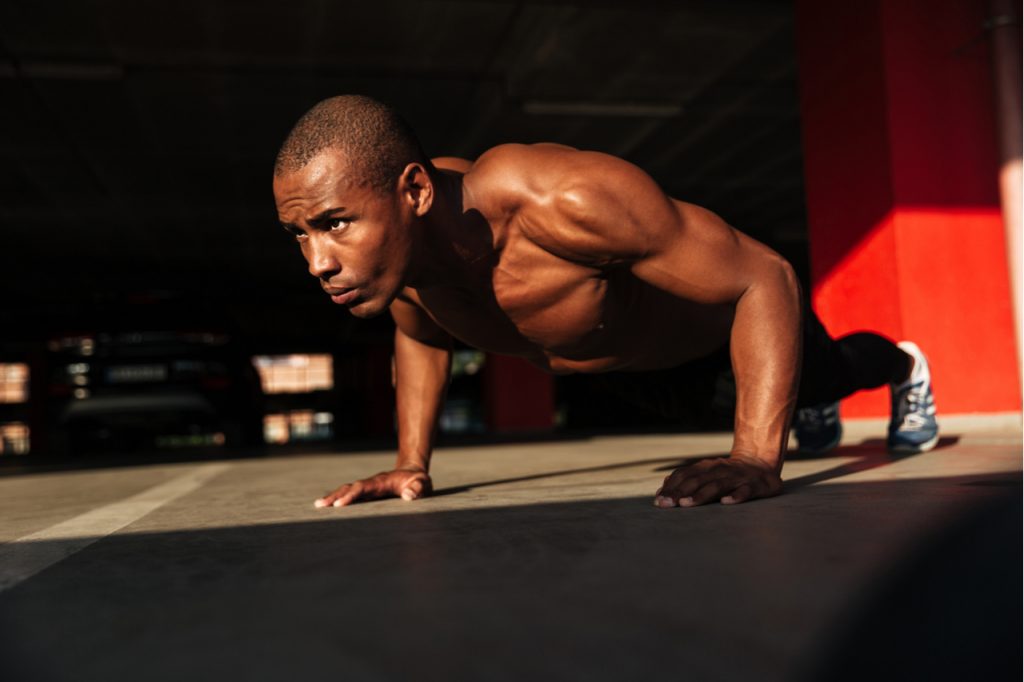A healthy man doing a plank indoors.