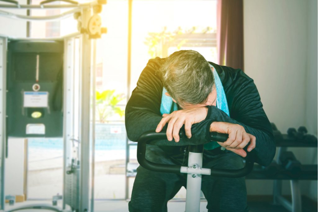 A man feeling tired or sleepy while on a stationary bike.