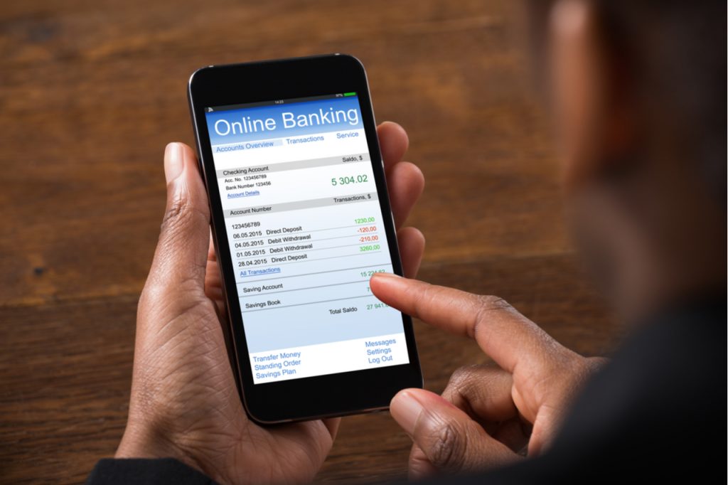 A man looking at his bank account details on his mobile phone. Possibly worrying about his financial health.