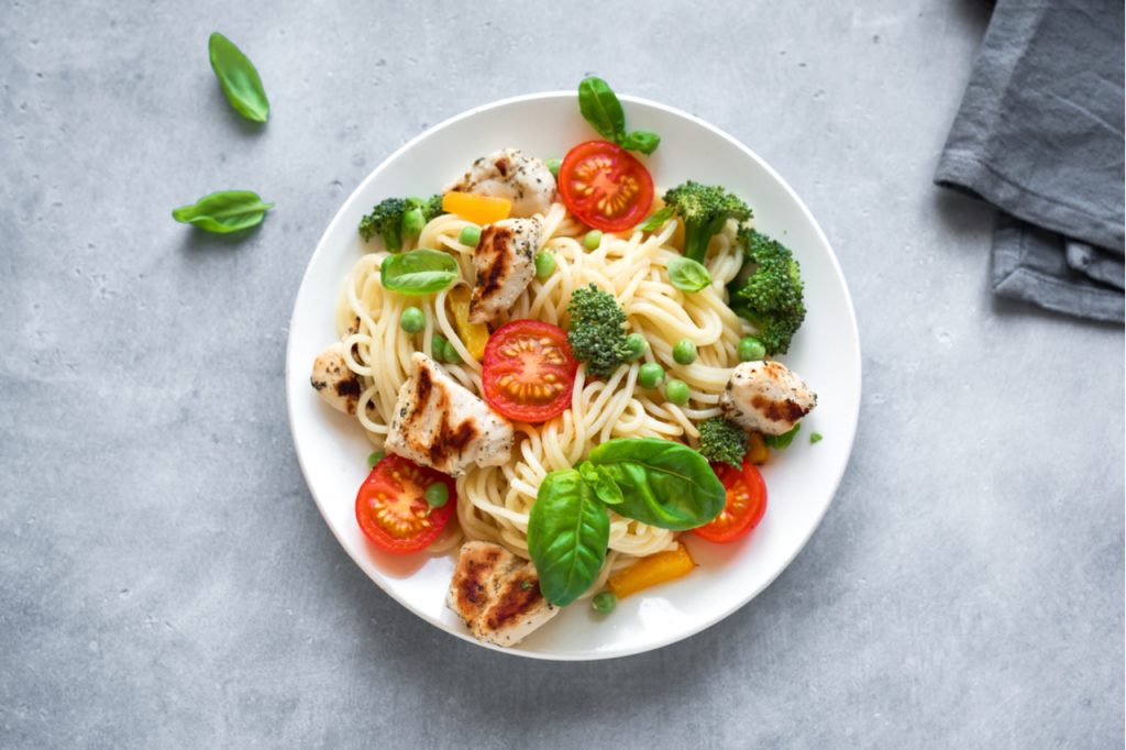 Spaghetti pasta with grilled chicken meat, vegetables and basil.
