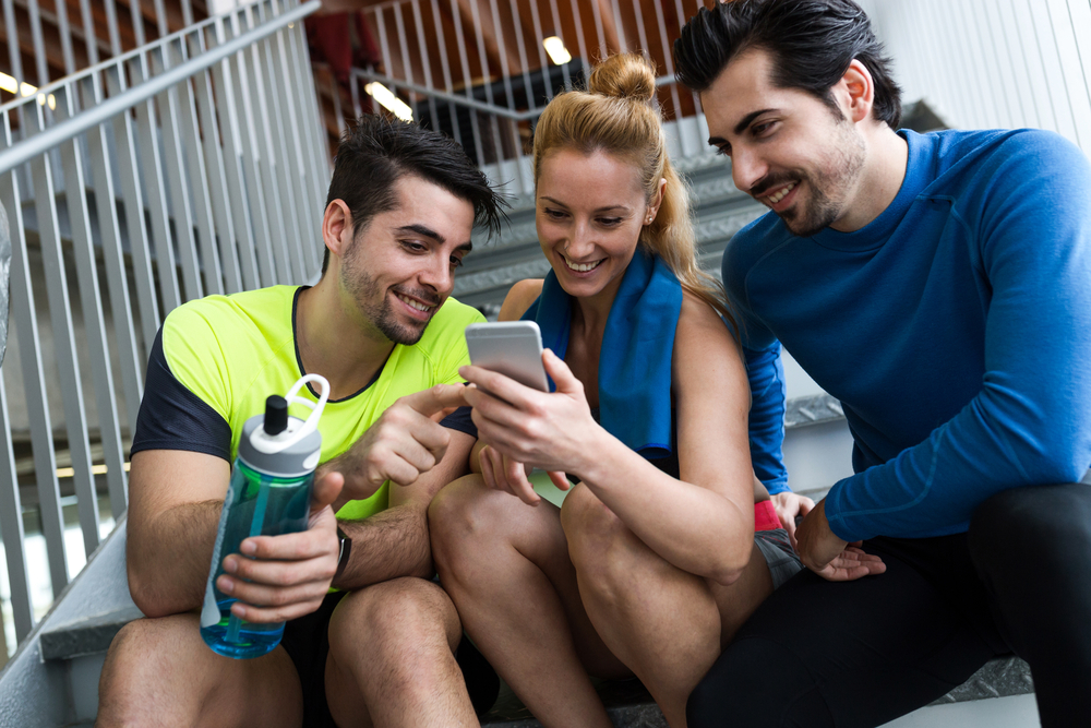 Portrait of group of sporty people using mobile phone in gym.