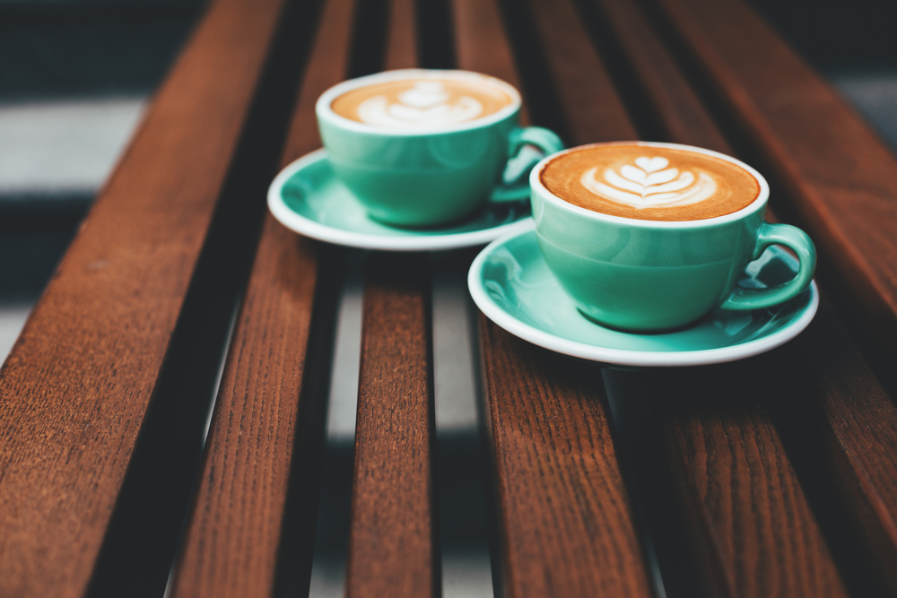 Two cups of cappuccino with latte art on wooden background