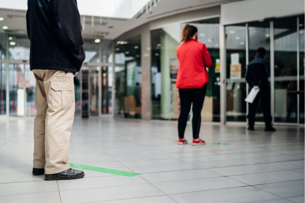 People standing in line front of bank/store due to coronavirus COVID-19 safe social distancing practice.