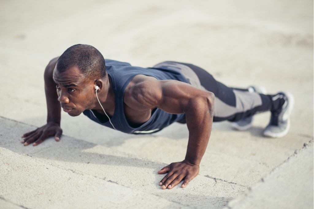 Portrait of a man doing push ups at the beach.