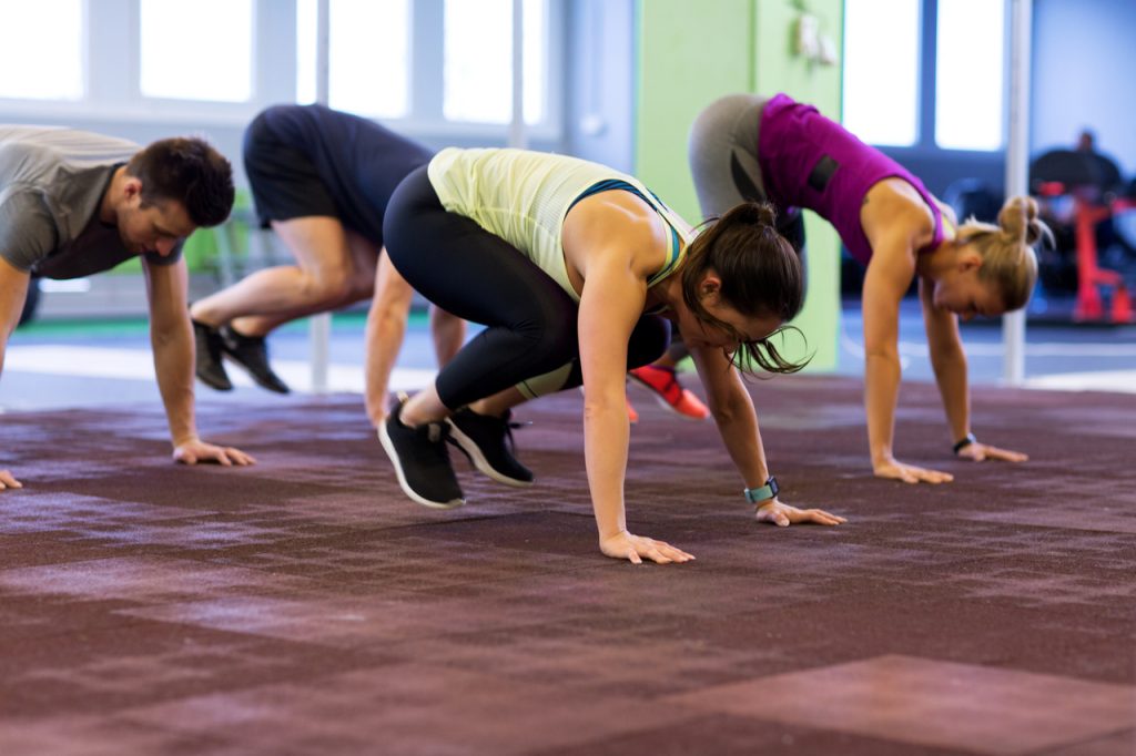 Group of people exercising doing burpees workout.