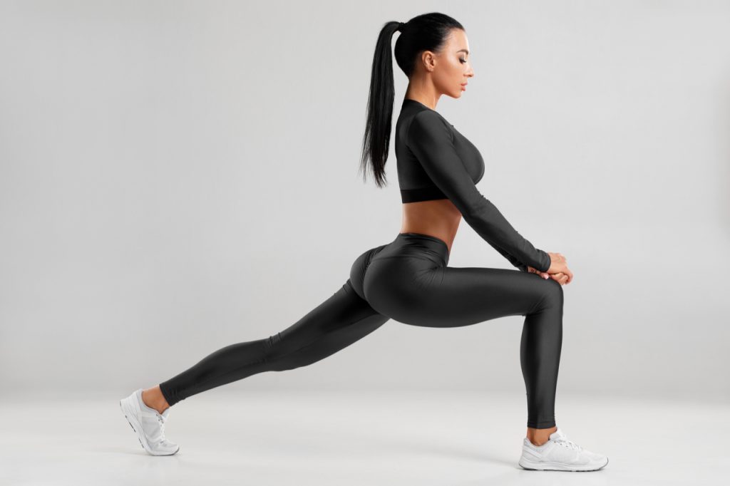 A fit woman doing front forward one leg step lunge exercise for butt.