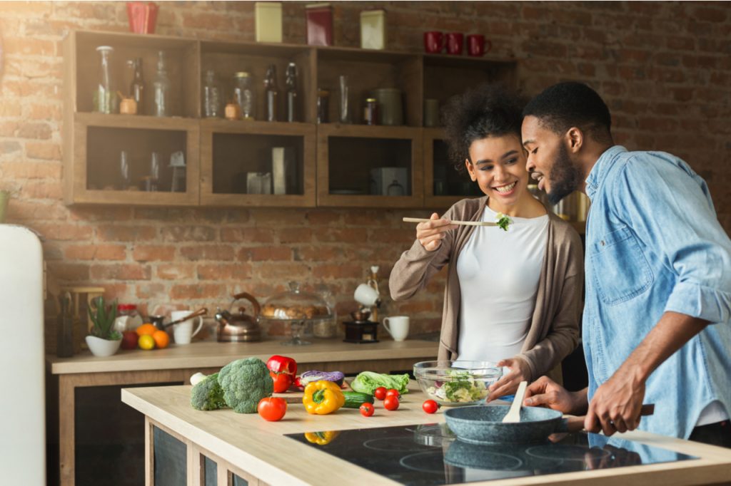 A young African American couple preparing salad together.