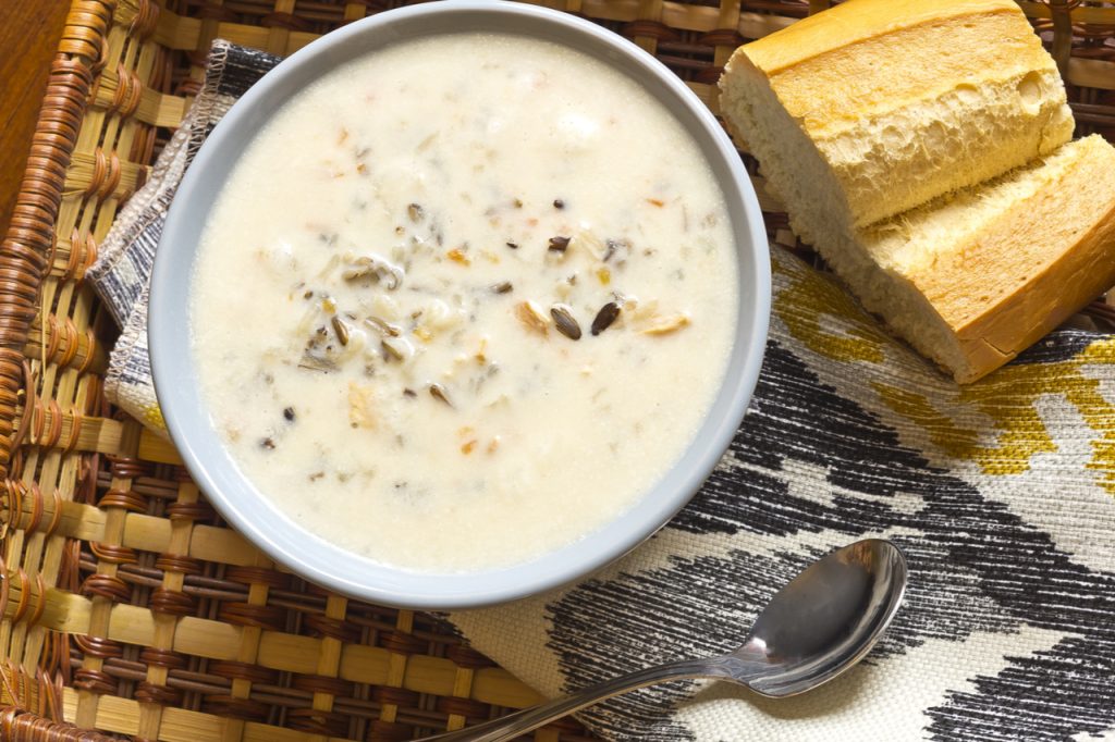 Creamy Chicken And Wild Rice Soup in a bowl with a sliced of bread for dipping.
