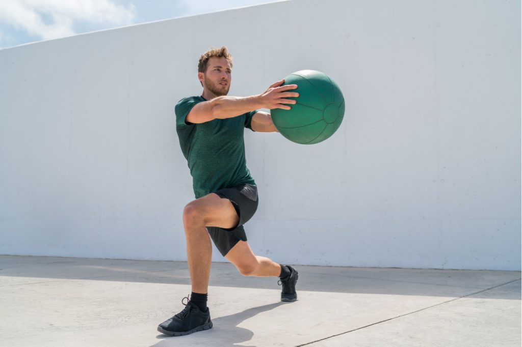 Man doing a Medicine ball Lunge with rotation.
