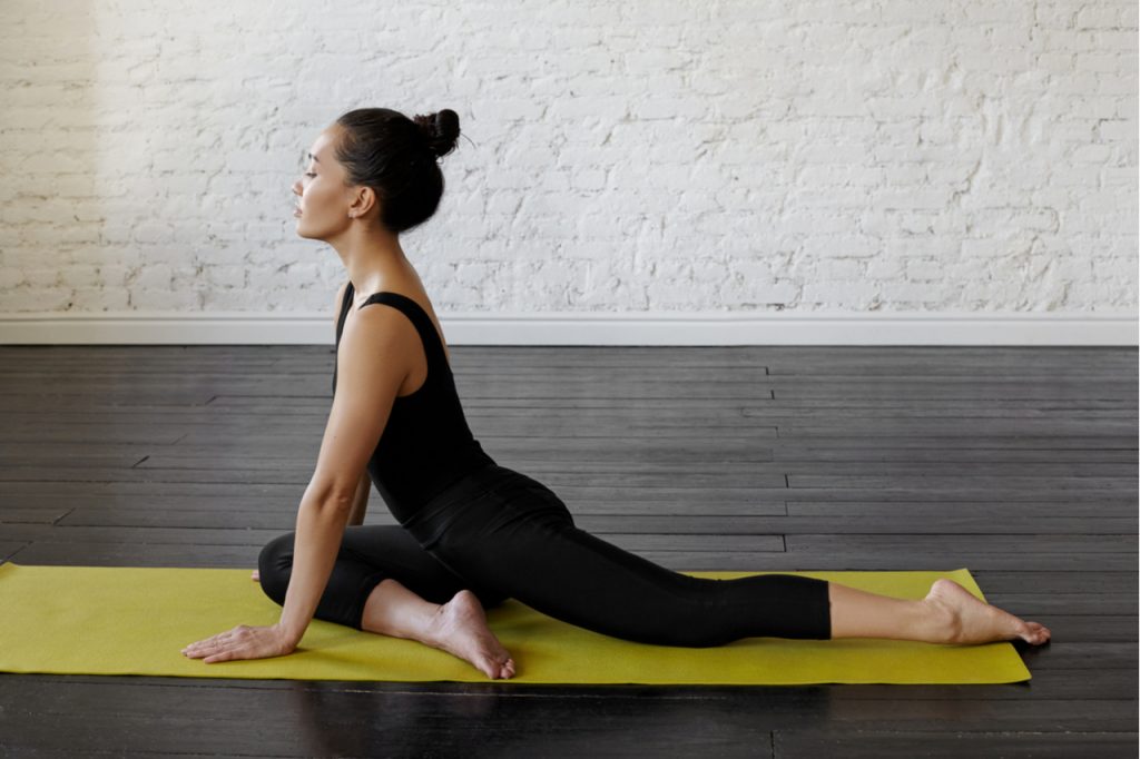 A woman doing the pigeon stretch.